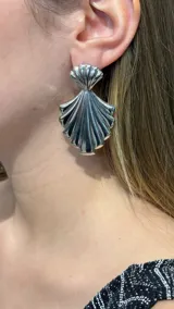 Aros colgantes plateados con diseño en forma de concha marina con relieve estriado.