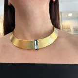 Gargantilla rígida dorada con trama delicada y cristal Swarovski engarzado. Cierre de mosquetón con cadena para regular el largo.