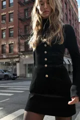 Top strapless confeccionado en tejido de terciopelo negro, con cierre frontal de botones metálicos dorados y bajo con abertura central.