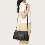 Cartera Guess modelo Angelica de color negro, confeccionada en material sintético con costuras en contraste y herrajes plateados. Cuenta con doble asa superior, correa ajustable y desmontable, y un detalle de cadena metálica colgante con las letras de la marca.