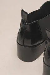 Botín chelsea de cuero vacuno color bordó con acabado charol, punta fina y elástico lateral negro. Posee un taco ancho y bajo de goma.