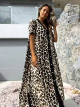 Vestido largo de corte holgado con estampado animal print de leopardo. Presenta una botonadura frontal completa sobre una franja vertical de color negro que recorre el centro de la prenda, cuello en V y mangas cortas.