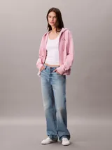 Buzo con capucha de Calvin Klein, de corte cropped y color rosado, confeccionado en mezcla de algodón y poliéster. Cuenta con cierre frontal de cremallera, cordones ajustables en la capucha y bolsillos tipo canguro. Presenta el logo de la marca bordado discretamente en el pecho.