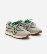 Championes de estilo retro inspirados en botines de fútbol, con capellada de poliuretano en color beige y detalles en azul marino. Presentan suela tractorada color caramelo, refuerzo en el talón y cordones combinados en gris y verde.