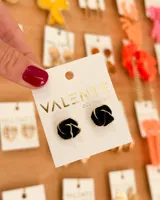 Par de caravanas negras con forma de rosa y borde dorado.