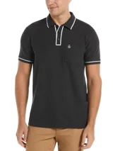 Polo gris oscuro de piqué de algodón con cuello clásico, tapeta de dos botones y manga corta con ribete blanco. Tiene un bolsillo de parche en el pecho izquierdo con el logo bordado de la marca.