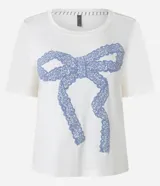 Blusa de pijama de viscosa color crema, con cuello redondo, mangas cortas y estampado frontal de un lazo grande en color azul.