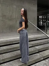 Pantalón de jean estilo wide leg, de tiro bajo, color gris lavado con efecto desgastado. Presenta corte recto y holgado en las piernas, con cierre frontal y bolsillos clásicos.