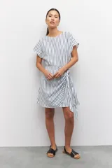 Vestido corto a rayas verticales azules y blancas, de corte suelto y manga corta. Presenta un lazo en uno de sus laterales.