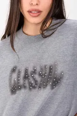 Remerón negro de corte oversize y mangas cortas, con estampa frontal difuminada estilo grafiti adornada con apliques de strass.