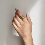 Anillo de diseño abierto con estructura de rejilla entrelazada, elaborado artesanalmente en metal con acabado plateado.