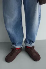 Zapatilla de cordones para hombre, confeccionada en piel con acabado de serraje en color beige. Presenta un diseño de perfil bajo con detalles de pespuntes decorativos y una suela ultrafina.