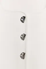 Top blanco de punto acanalado, con escote cuadrado y tirantes anchos. Presenta un cierre frontal decorativo con cinco botones metálicos plateados con forma irregular. El bajo es asimétrico y redondeado.