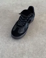 Zapatillas urbanas de cuero vacuno color negro, con suela alta y cordones.
