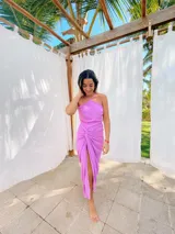 Vestido largo color naranja, con escote halter cruzado y falda tipo pareo con tajo lateral. Confeccionado en tela crepé con caída fluida.