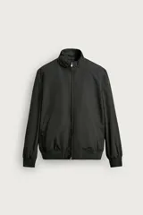 Cazadora regular fit de color negro confeccionada en tejido técnico repelente al agua. Presenta cuello subido, manga larga, bolsillos de vivo en la cadera, cierre frontal de cremallera y acabados en rib elástico en los puños y el bajo.