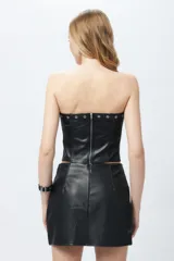 Top strapless negro en símil cuero con costuras tipo corsé y apliques de tachas, cuenta con un cierre metálico a la vista en la espalda.