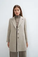 Saco corto entallado de lana fina, con cuello solapa, manga larga y cierre frontal con botones. Presenta un diseño clásico con textura de espiga en tonos tierra.