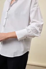 Camisa celeste de corte oversize, con mangas largas, cuello camisero y cierre frontal de botones.