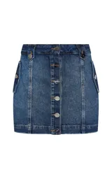 Short pollera de jean de denim azul, de corte recto y tiro alto, con cierre frontal de botones metálicos visibles, trabillas para cinturón y costuras verticales decorativas en el frente.