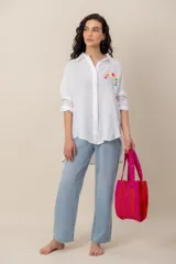 Camisa blanca de lino de corte oversize, con mangas largas y detalle de bordado colorido en el pecho.