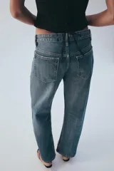 Jeans rectos de tiro medio en denim negro con efecto lavado. Presenta diseño de cinco bolsillos, trabillas para cinto y bajo con vuelta marcada. Cierre frontal con botones metálicos ocultos.