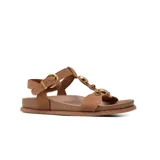 Sandalias planas de gamuza color marrón, con tiras anchas, hebilla metálica dorada de ajuste y detalles de apliques circulares dorados en el empeine.