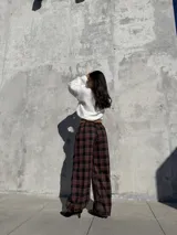 Pantalón de viyela con estampado a cuadros en tonos bordó y negro. Presenta un diseño de silueta amplia con cintura elástica y puños ajustados en los tobillos.