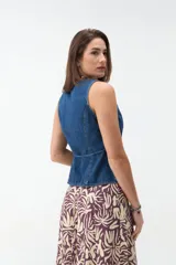 Chaleco de denim color beige, sin mangas, con escote en V, cierre frontal con botones y lazo ajustable en la cintura.