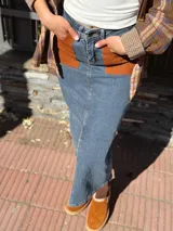 Falda midi de denim con elastano, corte recto y tajo frontal. Presenta bolsillos delanteros de cuero en color tostado y diseño clásico.