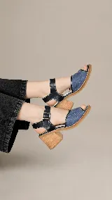 Sandalias de cuero combinadas en azul y negro, con diseño de textura croco en la capellada, costuras en contraste y taco ancho de madera. Poseen tira al tobillo con hebilla metálica regulable.