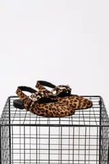 Chatitas de cuero con estampado animal print, puntera cerrada y talón descubierto. Presentan doble tira con hebillas y tachas.