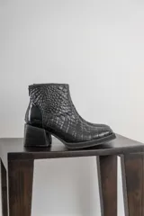 Conjunto de dos piezas compuesto por una musculosa de cuello redondo y un pantalón de corte recto, ambos en color negro. El pantalón incluye un cinturón ancho con hebilla metálica circular.