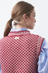 Chaleco tejido de algodón y acrílico, color rojo y blanco con patrón geométrico. Tiene cuello redondo y bordes acanalados en rojo.