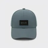 Gorro con visera gris con un parche rectangular negro en el frente con la inscripción 'blʌck'.