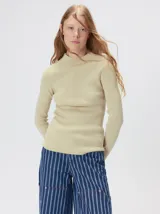 Remera de cuello alto tipo polera, confeccionada en tela rib con textura acanalada y ajuste al cuerpo. Presenta mangas largas y un pequeño bordado distintivo en la parte inferior.