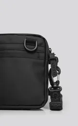 Mini bolso negro de estilo modular, confeccionado en tejido tracker impermeable. Presenta tres compartimentos con cierre y correa ajustable para llevar al hombro o cruzado.