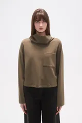 Buzo de cuello alto tipo polera, color verde oliva, con corte holgado, mangas largas y un bolsillo frontal aplicado en el pecho.