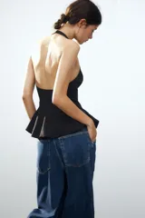 Top rosa claro, entallado, con cuello halter que se abrocha en la nuca y espalda descubierta. El bajo tiene un corte peplum acampanado.