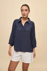 Camisa negra de calce relajado, con mangas 3/4, cuello clásico y cierre frontal con botones. Presenta detalles calados en la parte superior.