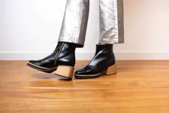 Botín de cuero negro con cierre lateral, punta cuadrada y taco de madera.