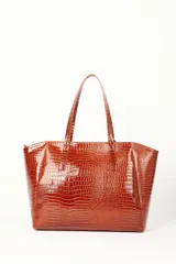 Bolso tipo shopper marrón con textura efecto cocodrilo y acabado charol, de gran tamaño y estructura semirrígida. Cuenta con doble asa de hombro y un pequeño estuche colgante desmontable.