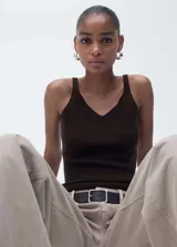 Top de punto fino color marrón chocolate, con cuello en pico y tirantes finos. Presenta un diseño entallado al cuerpo.