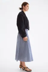 Pollera midi de corte acampanado, con diseño a rayas en azul marino y blanco. Presenta tiro alto y una amplia cintura elástica fruncida en punto smock.