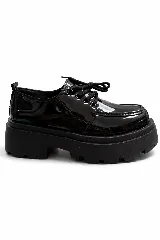 Mocasin de charol negro con cordones y suela de plataforma dentada.