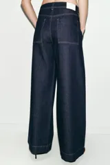 Jeans de tiro medio con corte wide leg y pernera ancha. Presenta bolsillos de plastrón en el delantero y cierre frontal con cremallera y botón.