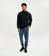 Pantalón jogger deportivo de color azul acero, con cintura elástica, cordón ajustable, bolsillos laterales con cierre de cremallera y puños elásticos en los tobillos.
