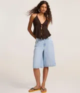 Blusa beige texturizada de corte halter con escote en V, lazo frontal ajustable en el busto y ruedo asimétrico ondulado.