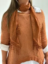 Sweater de punto color naranja con diseño asimétrico, que incluye una bufanda a juego con detalles bordados y una camisa blanca de base integrada.