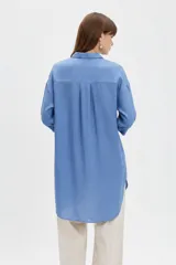 Camisa blanca de viscosa de corte oversize, con cuello camisero, cierre frontal de botones y bolsillo ojal en el pecho.